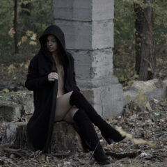 Naked girl in a coat with a hood sits posing in an autumn park. Nude photo by Pablo Incognito
