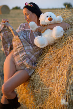 Nude photo shoot with a teddy bear in the hay