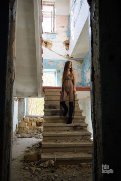 Nude girl in a transparent dress on the stairs in an abandoned
