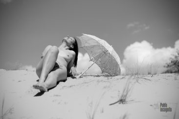 Nude lies on the sand under an umbrella