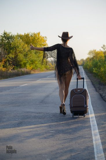 Hitchhiking girl, in a hat with a suitcase