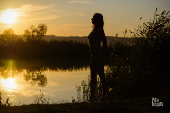 Woman profile silhouette by the river at sunset