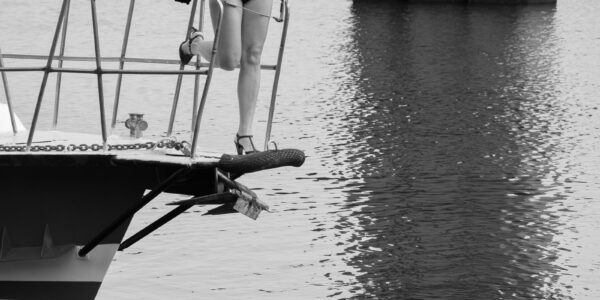 Black and white nude. A girl in a transparent bodysuit on the bow of the yacht. Photo by Pablo Incognito