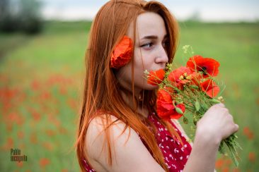 Red-haired young girl with a bouquet of poppies
