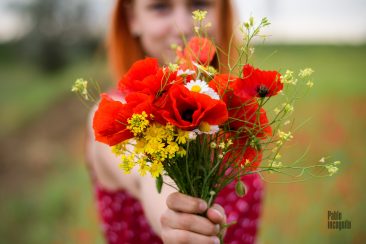 A bouquet of wild flowers in the hand of a red-haired girl