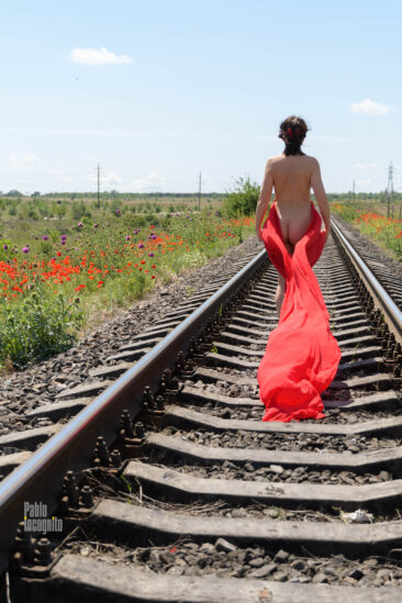 A naked girl walks along the railroad ties