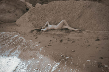 Naked woman lying on the wet sand