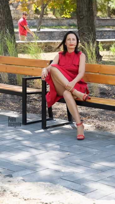 Girl in red sits cross-legged on a bench photo