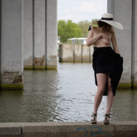 Topless, girl in a hat under the bridge by the river nude photo