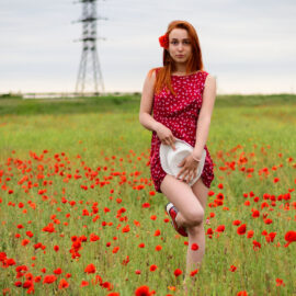 Photo of a young girl in a red dress in a field of poppies