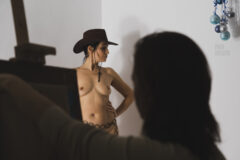 Model in cowboy hat posing nude for artists in studio