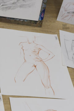 Figure drawing of a nude model posing for artists in a photo studio