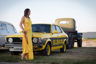 Woman in long yellow dress and yellow Subaru