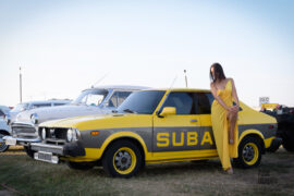 A girl in a long yellow dress poses near a yellow car. Nude photo session by Pablo Incognito