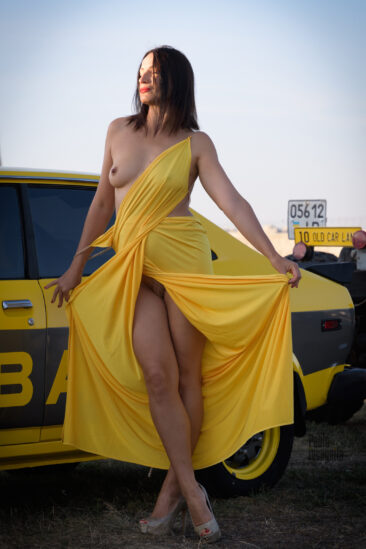 Woman in luxurious dress near yellow Subaru