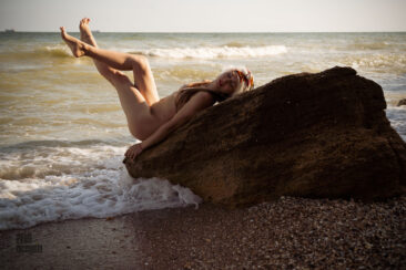 Naked nudist on a rock on the beach