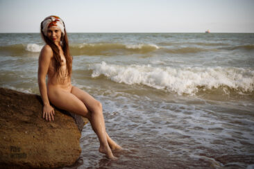 Beautiful nudist on a stone on the seaside nude