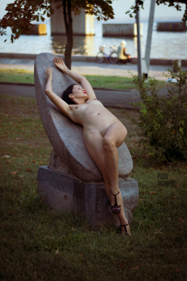 A naked girl lies on a stone in the park. Nude photo by Pablo Incognito