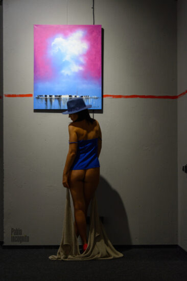 The visitor of the exhibition poses bottomless near the painting, nude photo