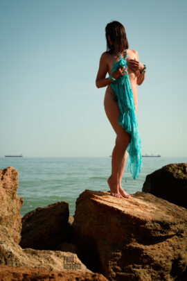 Nude girl with a turquoise cape on the stone. Nude photographer Pablo Incognito