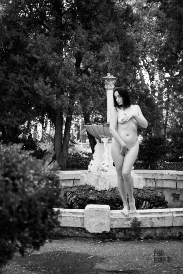 A naked girl poses like a garden statue by the fountain. Nude photographer Pablo Incognito