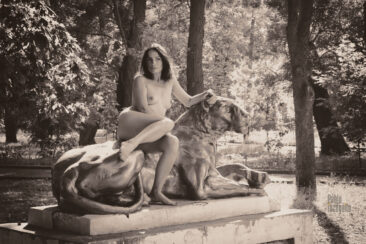 Nude girl and garden sculpture Lioness. Nude in the park. Pablo Incognito