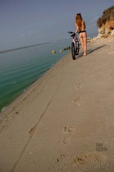 Naked girl with a bicycle on the river bank. Nude photo by Pablo Incognito