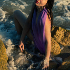 Wet girl in a lilac cape posing nude on the beach. Photo by Pablo Incognito