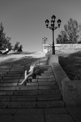 Nude woman posing while sitting on city steps nude