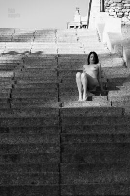 Nude girl sitting on the steps in the street
