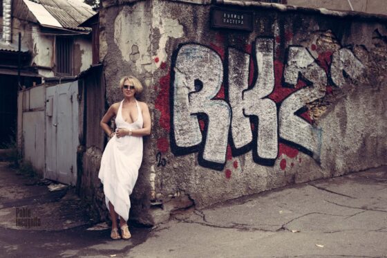 Blonde with deep cleavage posing near graffiti photo
