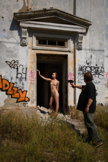 Nude model on the porch of a dilapidated building