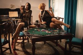 Brunette and blonde smoke sitting on the poker table